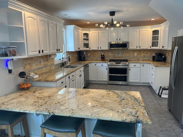 kitchen with pendant lighting, sink, white cabinets, light stone counters, and stainless steel appliances