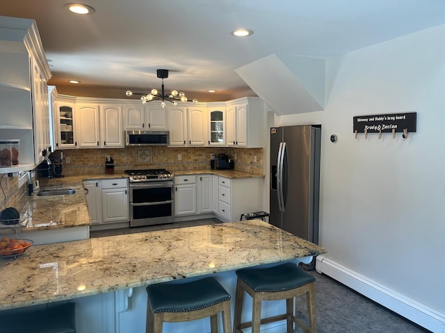 kitchen featuring pendant lighting, appliances with stainless steel finishes, white cabinetry, a baseboard radiator, and kitchen peninsula