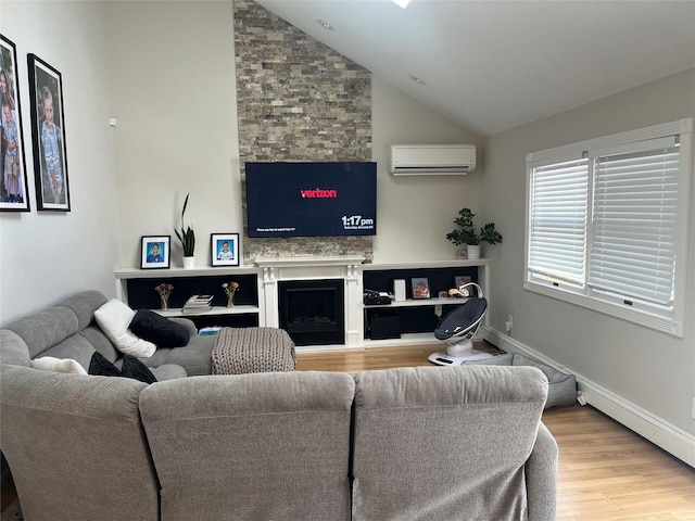 living room featuring vaulted ceiling, a fireplace, a wall unit AC, and light hardwood / wood-style flooring