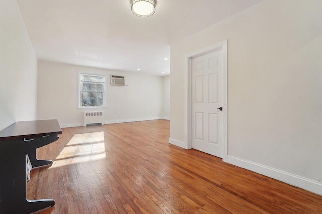 interior space featuring radiator, light hardwood / wood-style flooring, and a wall unit AC