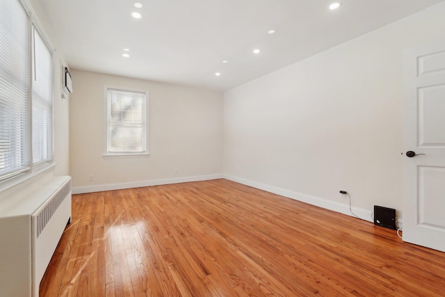 spare room with radiator heating unit and light hardwood / wood-style floors