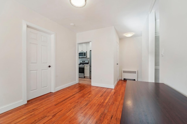 hallway with radiator heating unit and wood-type flooring