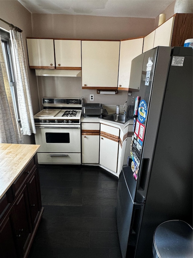 kitchen featuring sink, dark wood-type flooring, white cabinetry, black fridge with ice dispenser, and white gas stove