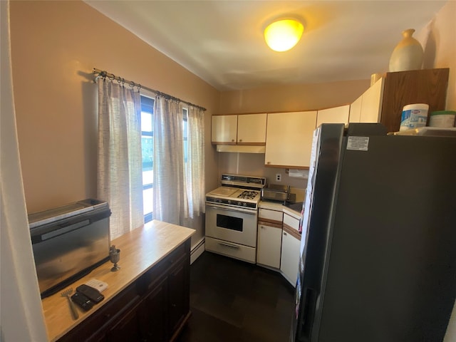 kitchen with black fridge, a baseboard heating unit, white gas stove, and white cabinets