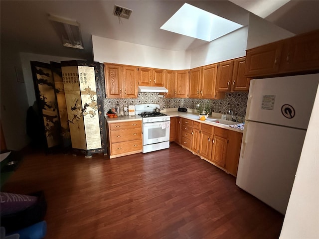 kitchen with sink, a skylight, dark hardwood / wood-style flooring, white appliances, and decorative backsplash