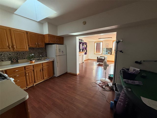 kitchen featuring tasteful backsplash, dark hardwood / wood-style flooring, a skylight, and white fridge