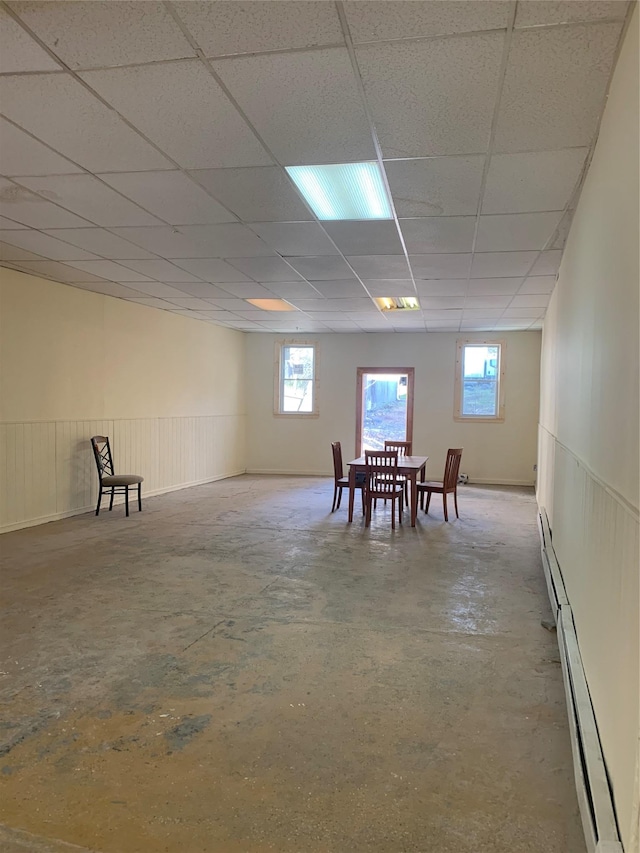 interior space with a baseboard heating unit and a drop ceiling