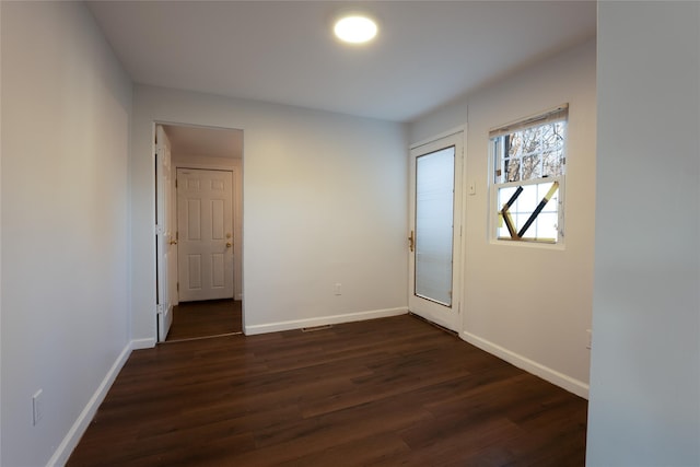 spare room featuring dark wood-type flooring and baseboards