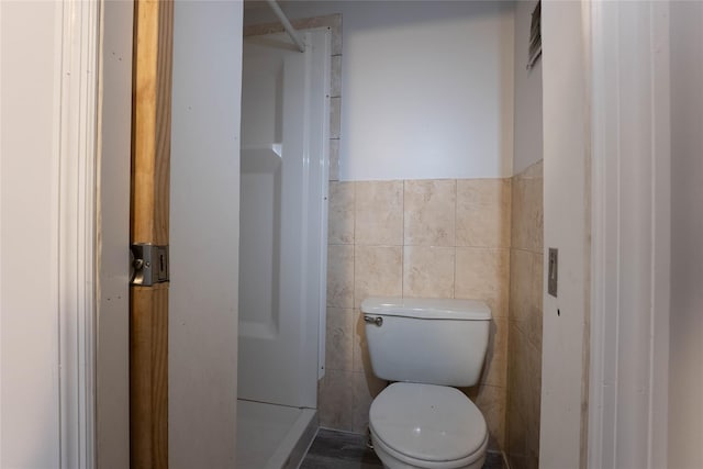 bathroom with tile walls and toilet