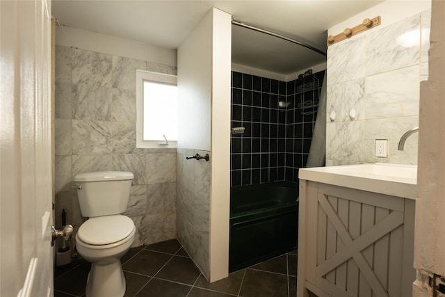 full bath with tile patterned floors, toilet, vanity, tile walls, and shower / tub combo