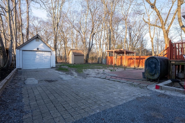 view of yard with a detached garage, fence, heating fuel, a deck, and an outdoor structure