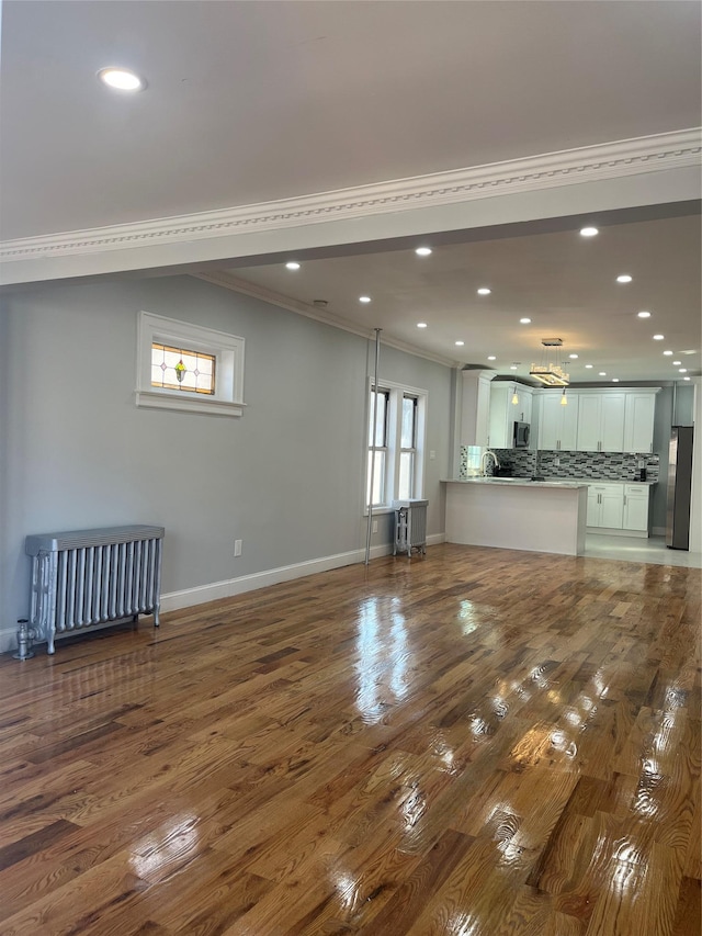 unfurnished living room featuring crown molding and wood-type flooring