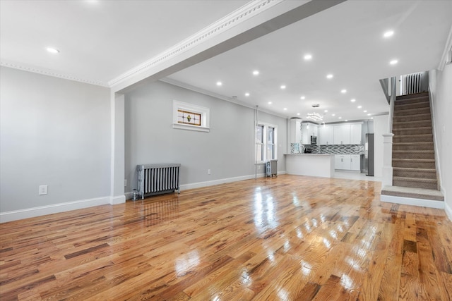 unfurnished living room featuring ornamental molding, radiator heating unit, and light hardwood / wood-style floors