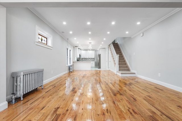 unfurnished living room featuring ornamental molding, radiator heating unit, and light hardwood / wood-style floors