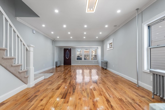 unfurnished living room with crown molding, radiator heating unit, and light hardwood / wood-style floors