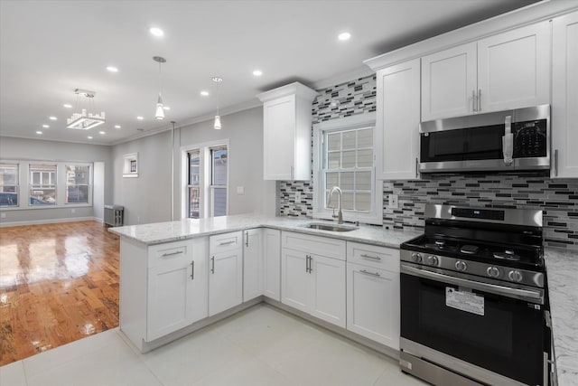 kitchen with sink, hanging light fixtures, appliances with stainless steel finishes, kitchen peninsula, and white cabinets