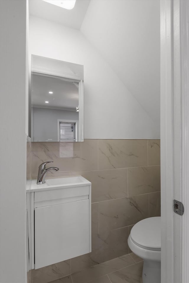 bathroom featuring tile patterned flooring, vanity, tile walls, and toilet