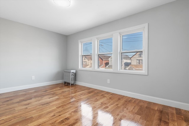 unfurnished room featuring radiator heating unit and light hardwood / wood-style flooring