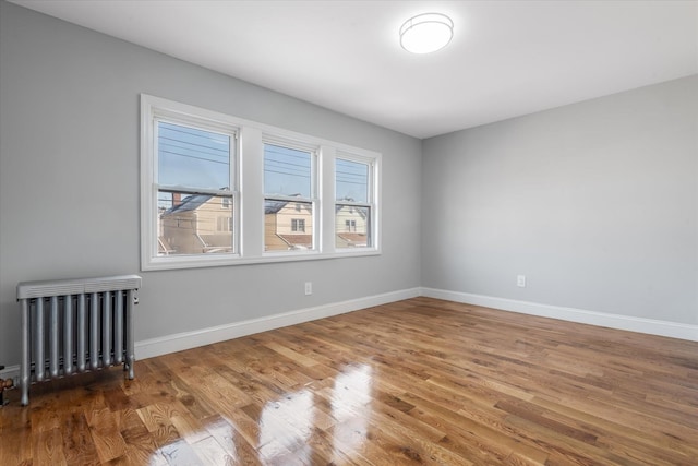 spare room featuring radiator and wood-type flooring