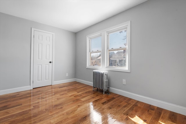 unfurnished room featuring radiator and hardwood / wood-style flooring