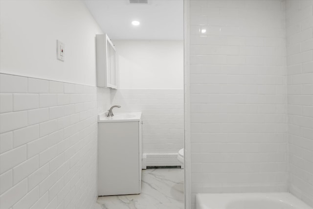 full bathroom featuring baseboard heating, vanity, toilet, and tile walls