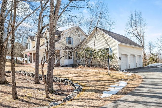 view of side of property featuring a garage, covered porch, and driveway