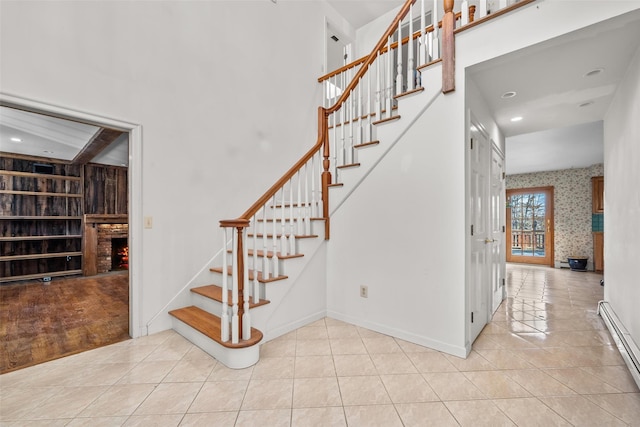 stairs featuring a baseboard heating unit, tile patterned flooring, baseboards, and wallpapered walls