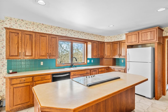 kitchen with light countertops, freestanding refrigerator, a kitchen island, a sink, and dishwashing machine