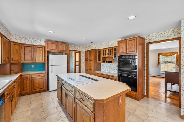 kitchen with black appliances, wallpapered walls, a baseboard heating unit, and brown cabinetry