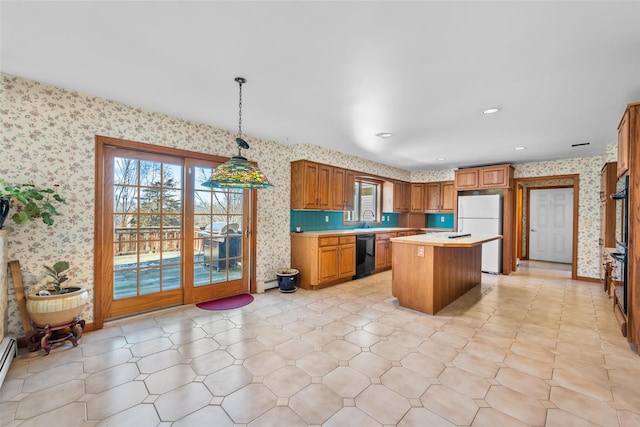 kitchen with brown cabinets, light countertops, a kitchen island, black appliances, and wallpapered walls