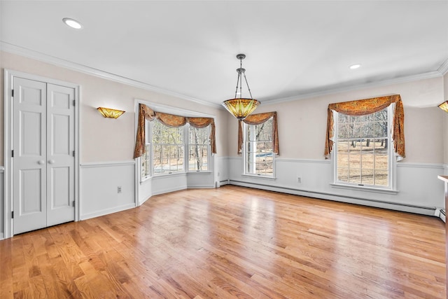 unfurnished dining area with a baseboard radiator, a wainscoted wall, crown molding, and wood finished floors