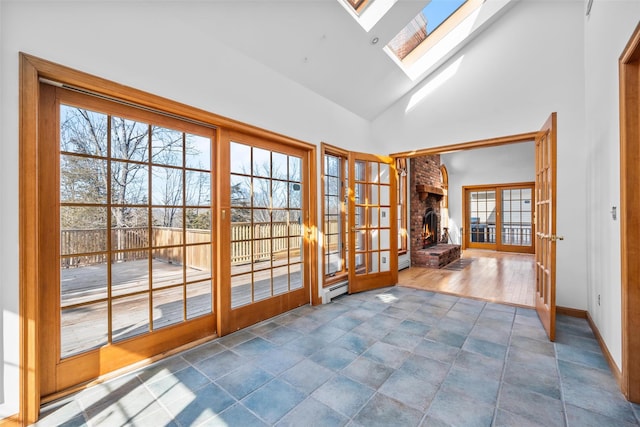 entryway with a skylight, baseboards, a baseboard radiator, french doors, and high vaulted ceiling