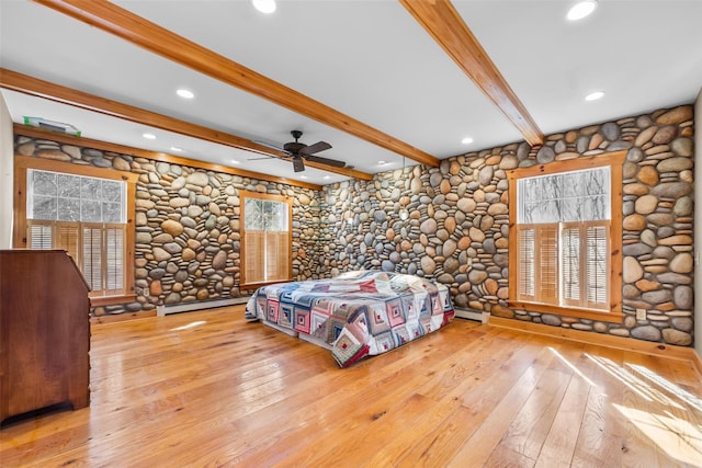 unfurnished bedroom featuring a baseboard radiator, multiple windows, and hardwood / wood-style floors