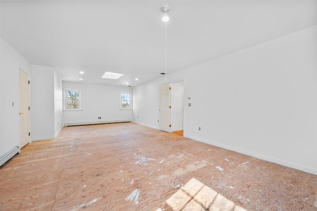 empty room with baseboard heating, a skylight, and baseboards