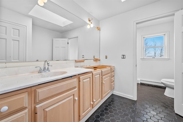 bathroom with a skylight, a baseboard radiator, toilet, vanity, and tile patterned floors