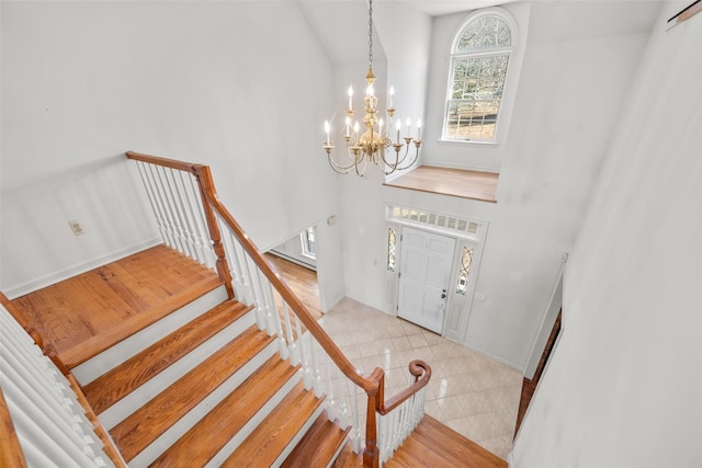 foyer entrance with stairs, a towering ceiling, an inviting chandelier, and tile patterned floors