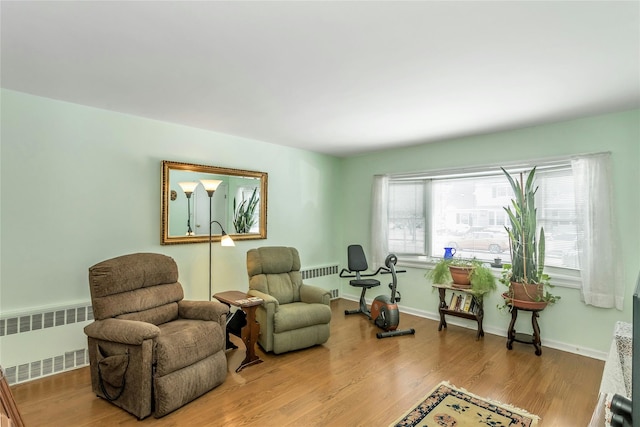 living area with radiator heating unit and light hardwood / wood-style flooring