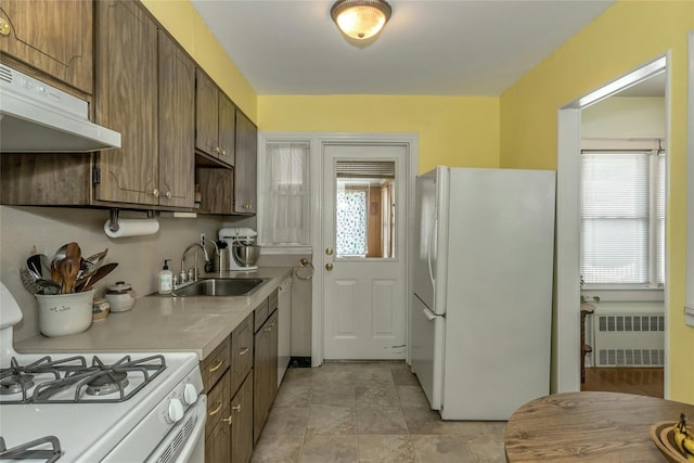 kitchen with white appliances, radiator heating unit, and sink