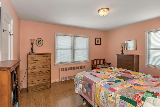 bedroom featuring radiator heating unit and wood-type flooring