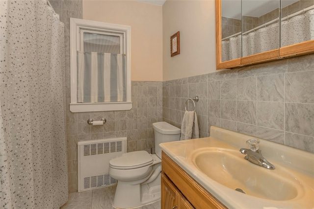 bathroom with tile walls, radiator heating unit, vanity, tile patterned floors, and toilet