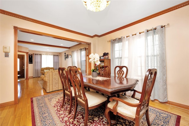 dining room with a notable chandelier, ornamental molding, and light wood-type flooring