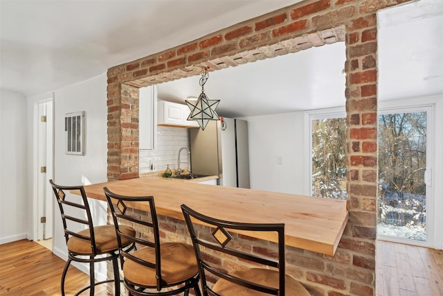 dining area with wet bar and light wood-type flooring