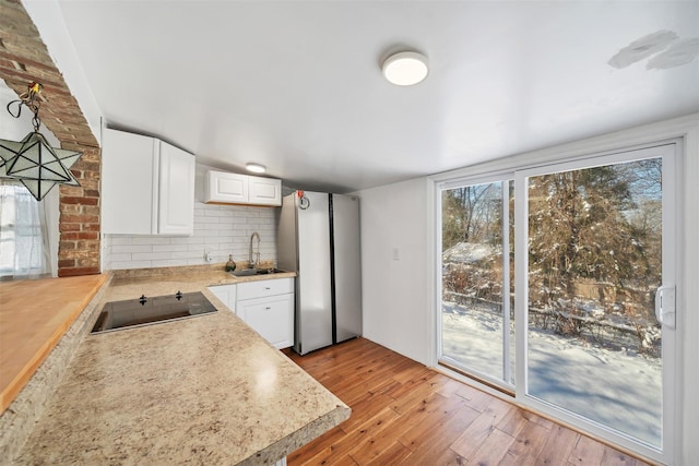 kitchen with sink, white cabinetry, decorative light fixtures, black electric cooktop, and backsplash