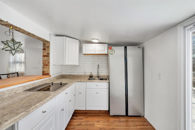 kitchen with pendant lighting, white cabinetry, black electric stovetop, and sink