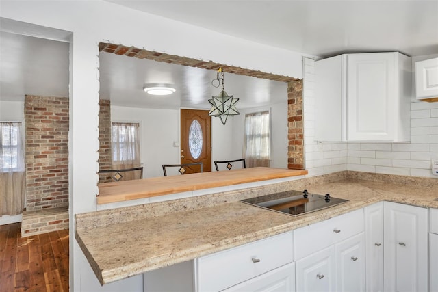 kitchen with dark wood-type flooring, decorative light fixtures, black electric cooktop, kitchen peninsula, and white cabinets