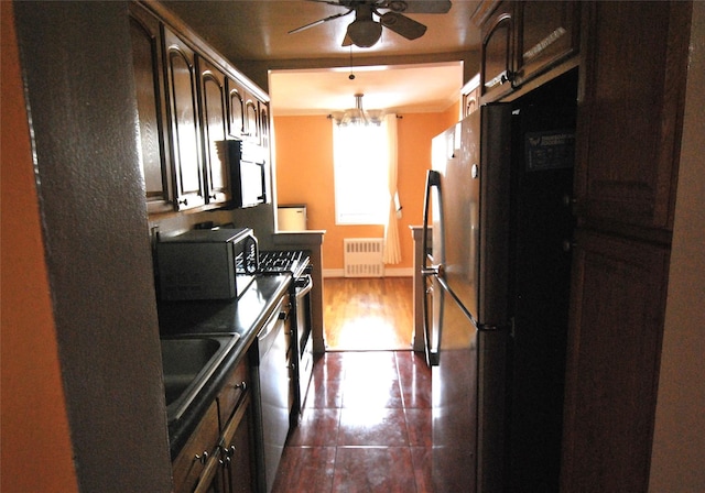 kitchen featuring radiator, ceiling fan with notable chandelier, sink, dark brown cabinetry, and stainless steel appliances