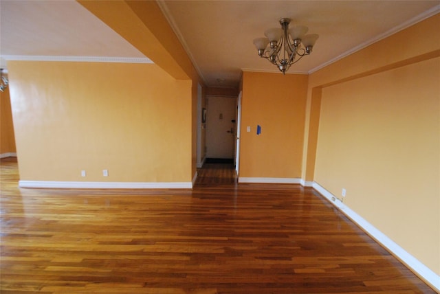 empty room featuring crown molding, wood-type flooring, and a chandelier