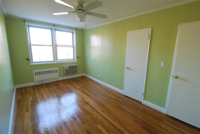 empty room featuring crown molding, an AC wall unit, radiator heating unit, and dark hardwood / wood-style flooring