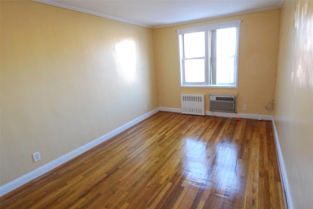 empty room with dark wood-type flooring, ornamental molding, radiator heating unit, and a wall unit AC