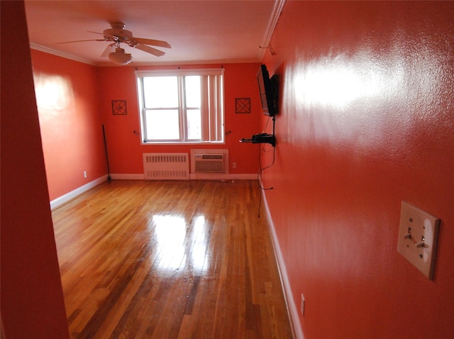 unfurnished room featuring a wall mounted air conditioner, wood-type flooring, ornamental molding, radiator, and ceiling fan